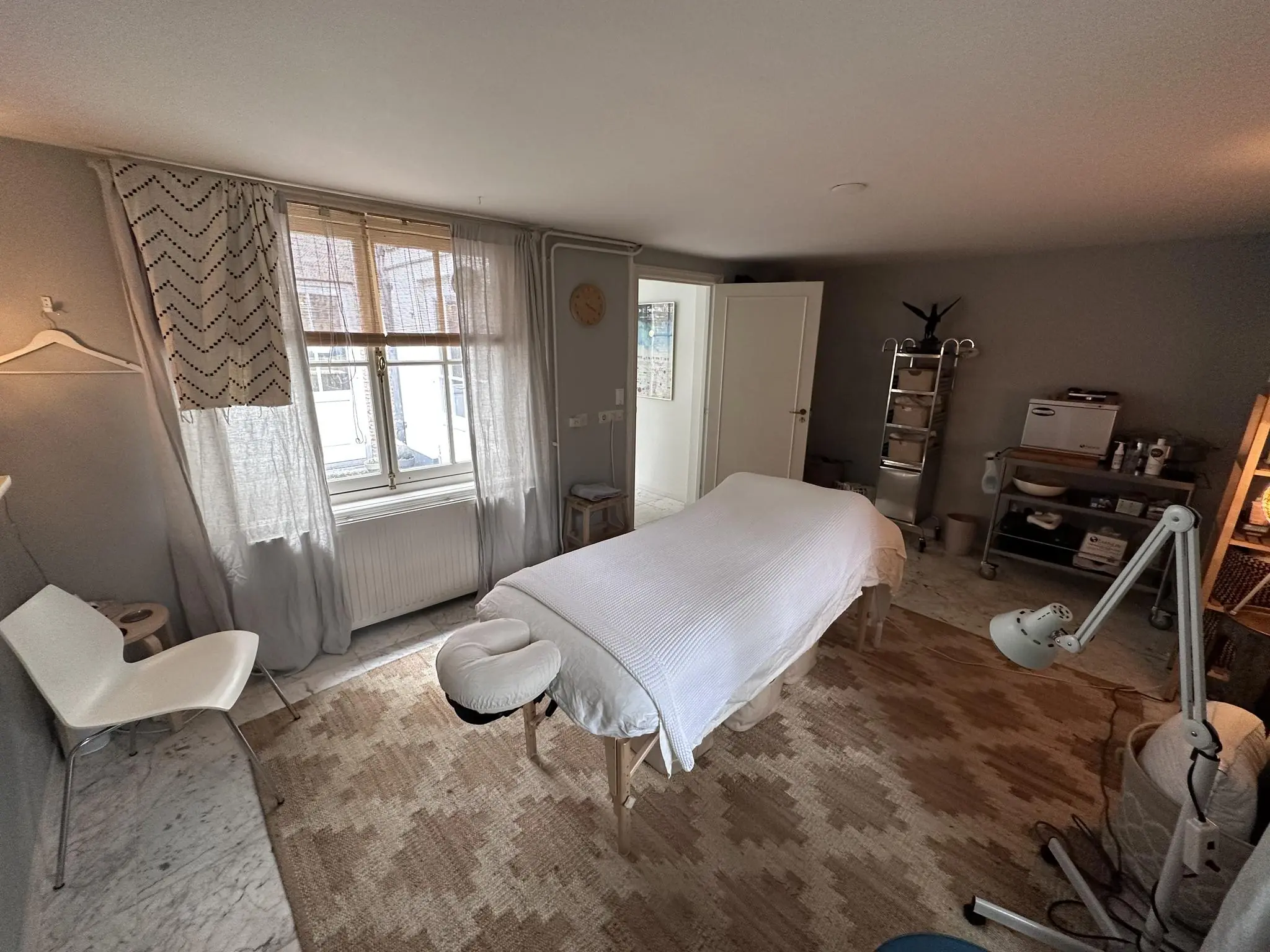 Rustige behandelkamer in de Eerste Lindendwarsstraat met een massagetafel, warme verlichting en verzorgingsapparatuur.